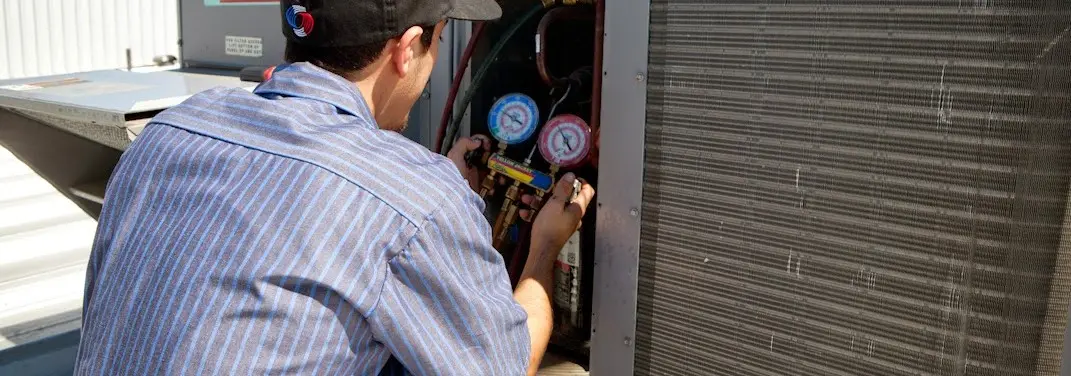 HVAC technician servicing a condenser unit in Gilmer